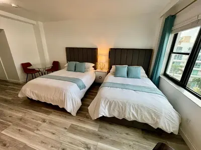two beds in a hotel room with a table and chairs at Directly on the Beach with Pool & Parking in Miami Beach