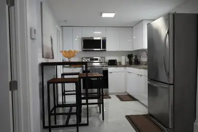 a kitchen with white cabinets and a stainless steel refrigerator at Charming two bedroom apartment. in Miami