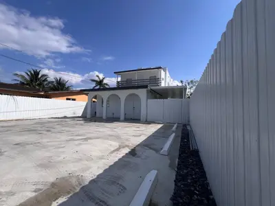 a white building with a fence next to a building at Charming two bedroom apartment. in Miami