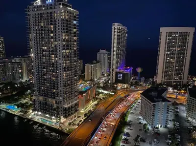 a city skyline with tall buildings and traffic at night at Cozy Beach Apartment with Full Kitchen & Ocean Views in Hallandale Beach
