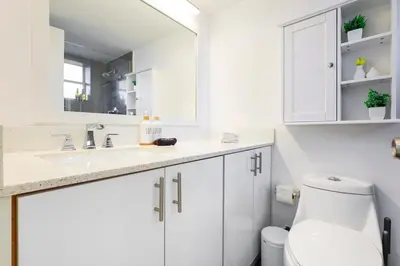 a white bathroom with a toilet and a mirror at La Marinita - Marina Views Pool Parking Location in Miami Beach