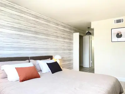 a bedroom with a large white bed with a wooden wall at Zen Vibe on the Beach /700 SqFt in Miami Beach