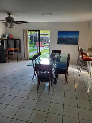 a dining room with a glass table and chairs at Cozy family home in quiet area, nice garden views. in Tamiami