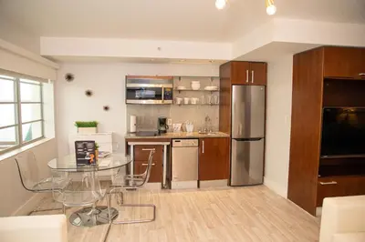 a kitchen with a glass table and stainless steel refrigerator at Strand Ocean Drive Suites in Miami Beach