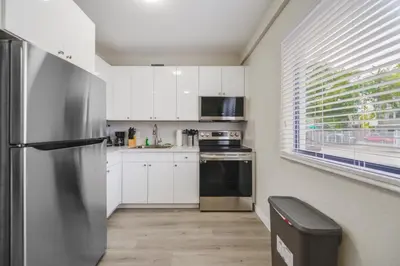 a kitchen with white cabinets and a stainless steel refrigerator at Amazing Experience in Calle Ocho in Miami