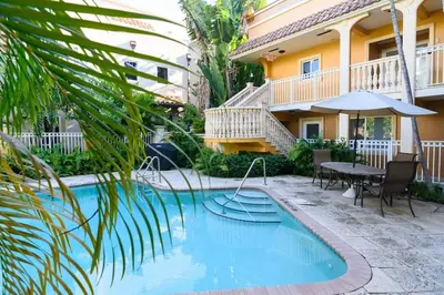 a pool in front of a house with a table and an umbrella at Las Olas Blvd Waterfront Apt in Fort Lauderdale