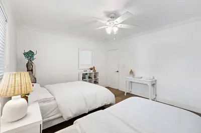 a white bedroom with two beds and a ceiling fan at Spacious Beach Apt in Las Olas Blvd in Fort Lauderdale