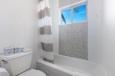 a white bathroom with a toilet and a window at Relaxing Beach Apt in las Olas Blvd in Fort Lauderdale