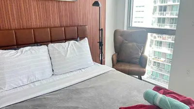 a bedroom with a bed and a chair and a window at Huge Studio POOL & GYM - Explore Miami's Heat in Miami
