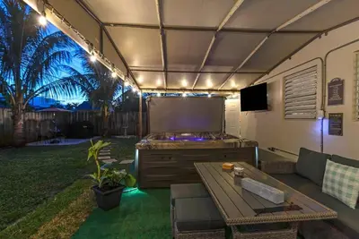 a outdoor living area with a couch and a television at 7-Person Luxury Spa, Fenced Paradise, Beach Vibes in Pembroke Pines