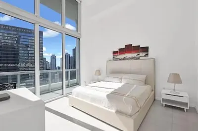 a white bedroom with a bed and a large window at 28th Floor Icon Brickell Penthouse with City Views in Miami