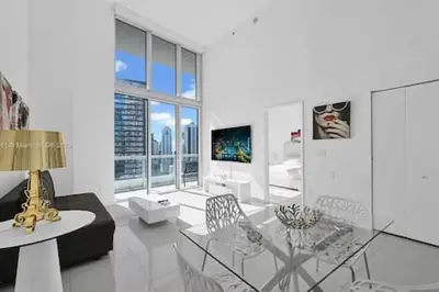 a white living room with a glass table and chairs at 28th Floor Icon Brickell Penthouse with City Views in Miami