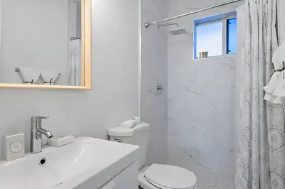 a white bathroom with a toilet and a sink at North Shore Oasis - Steps to Miami Beach Bliss in Miami Beach
