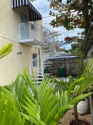 a house with a white staircase next to a building at ZION Miami Design District 2 Bedroom amongst the trees! in Miami