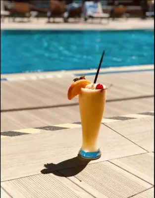 a drink sitting on a table next to a pool at Compact & Comfy, BeachWalk Studio for Small Groups in Hallandale Beach