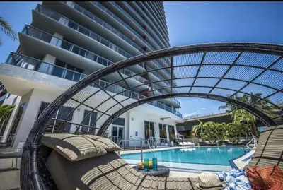 a resort with a swimming pool with a rattan bed next to a building at Compact & Comfy, BeachWalk Studio for Small Groups in Hallandale Beach