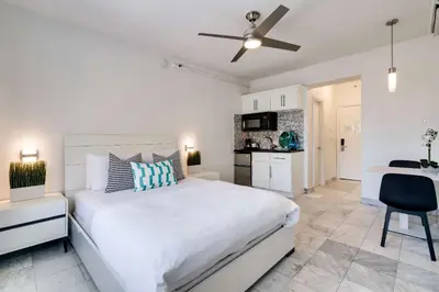 a white bedroom with a large bed and a kitchen at Best location by the Beach ! Free WiFi - TV - All amenities 103 in Miami Beach