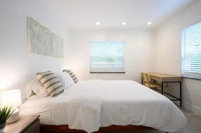 a bedroom with a large white bed and a desk at Beautiful And Comfortable Apt in Victoria Park in Fort Lauderdale
