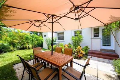 a wooden table and chairs under an umbrella at Beautiful And Comfortable Apt in Victoria Park in Fort Lauderdale