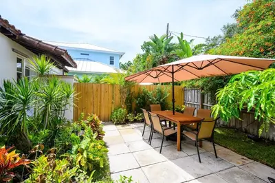 a patio with a wooden table and chairs and an umbrella at Beautiful And Comfortable Apt in Victoria Park in Fort Lauderdale