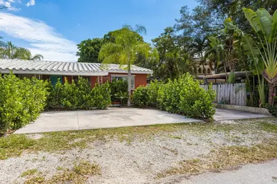 a red house with a fence and bushes at Lovely Rental Unit with free Parking on Premises in Fort Lauderdale