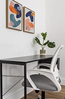 a desk with a white chair and paintings on the wall at Stylish 2 BR Condo - Free Parking on Premises in Fort Lauderdale