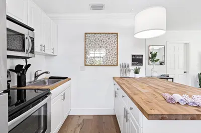 a kitchen with white cabinets and a wooden counter top at Bright and Spacious 2 BR Apartment in Fort Lauderdale