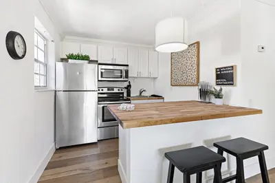 a kitchen with white cabinets and a wooden counter top at Bright and Spacious 2 BR Apartment in Fort Lauderdale