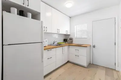 a kitchen with white cabinets and a white refrigerator at Lovely Studio in the Heart of Victoria Park in Fort Lauderdale