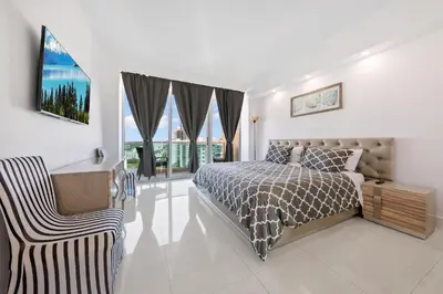 a bedroom with a bed and a chair and windows at Oceanfront Luxury Penthouse On The Beach 3 Bedroom in Hollywood