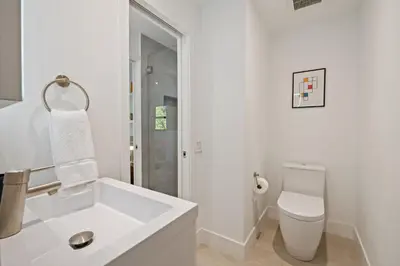 a white bathroom with a toilet and a sink at Coconut Grove Mid-Century Jungle Oasis in Miami