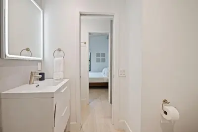 a white bathroom with a sink and a mirror at Coconut Grove Mid-Century Jungle Oasis in Miami