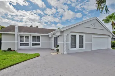 a large white house with a driveway at Spacious 4 bedrooms, 2 bathroom house with pool in Miramar