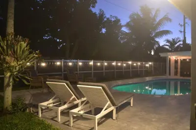 a pair of chairs next to a swimming pool at night at Spacious 4 bedrooms, 2 bathroom house with pool in Miramar
