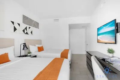 a white bedroom with two beds and a tv at Bayview Luxury: 3BR Pools Oceanfront Amenities in Hollywood