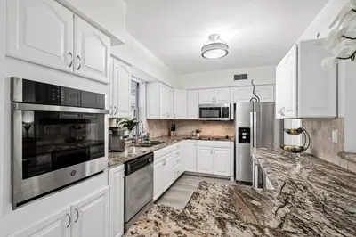 a kitchen with white cabinets and marble counter tops at Villa Oasis 3 Miles to Hard Rock Stadium & Casino, Guitar Hotel Nearby, Pool, Game Room, Sleeps 12, 15 Min to Beach in Pembroke Pines