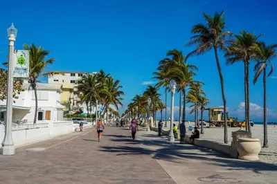 a beach with palm trees and people walking down a sidewalk at Villa Oasis 3 Miles to Hard Rock Stadium & Casino, Guitar Hotel Nearby, Pool, Game Room, Sleeps 12, 15 Min to Beach in Pembroke Pines