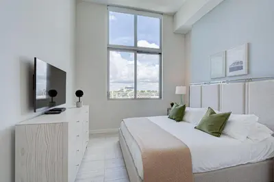 a white bedroom with a bed and a television at 3900-502GJ DESIGN DISTRICT, CONDO 2 BEDROOMS & 2 BATHROOMS in Miami