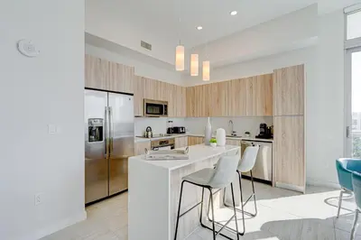 a kitchen with a white counter and stools at 3900-602LG DESIGN DISTRICT, CONDO 2 BEDROOMS & 2 BATHROOMS in Miami