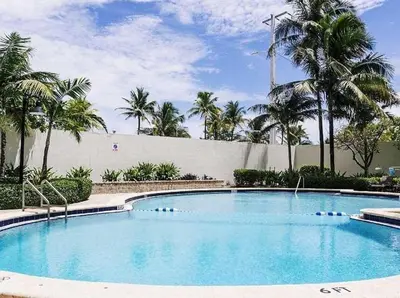 a large swimming pool with palm trees in the background at Sian Oceanfront Condos in Hollywood