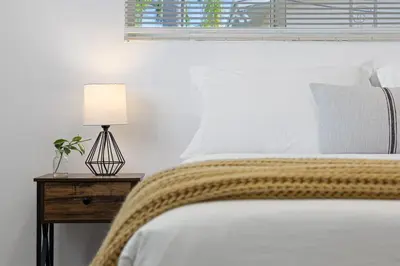 a bed with a blanket and a lamp on a night stand at The Perfect Escape @Lake Ridge in Fort Lauderdale