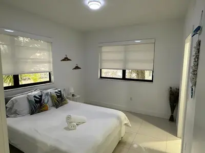 a bedroom with a white bed with two windows at Modern apartment steps the beach in Miami Beach