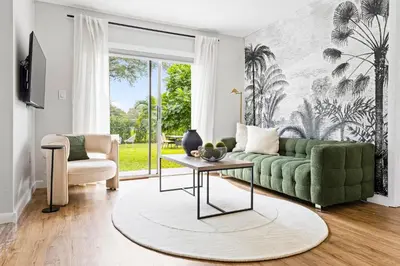 a living room with a green couch and a table at Hidden Garden: A Serene Miami Escape in Cutler Bay