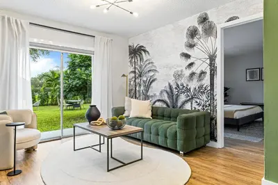 a living room with a green couch and a table at Hidden Garden: A Serene Miami Escape in Cutler Bay