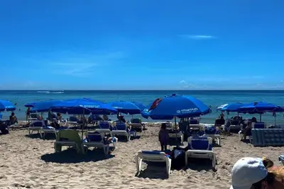 a beach with chairs and blue umbrellas and the ocean at Bright Miami Beach Stay with Amazing Views, Full Kitchen -A in Hallandale Beach