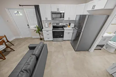 a kitchen with a couch and a stainless steel refrigerator at Progresso Apartments & Homes by Lowkl in Fort Lauderdale