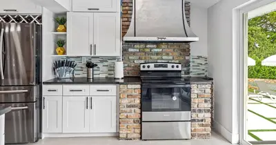 a kitchen with white cabinets and a brick wall at New Spectacular 6BR Bliss - Pool - Spa & Pickell in Miami
