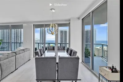 a dining room with a table and chairs and windows at Apartment 3B/3B Bay View in Hallandale Beach
