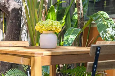 a white vase with yellow flowers on a wooden table at Welcoming Airbnb Walkig distance to Las Olas Blvd in Fort Lauderdale