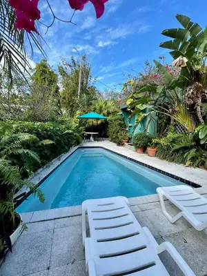 a swimming pool with two lawn chairs and an umbrella at Welcoming Airbnb Walkig distance to Las Olas Blvd in Fort Lauderdale